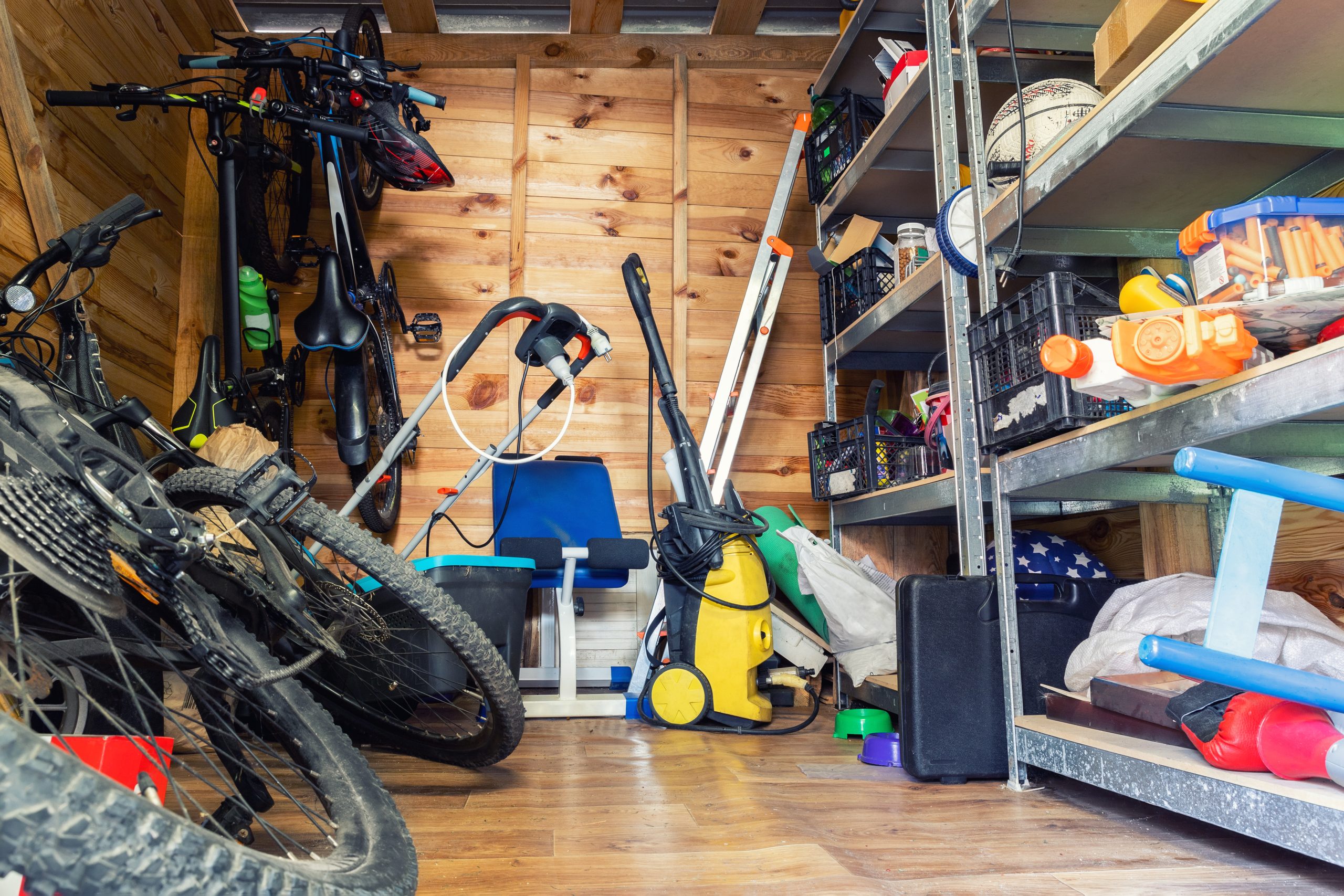 A storage shed with bikes, shelves, and equipment in a relatively organized space.