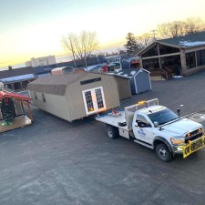 A 16x48 ft shed is being loaded onto a delivery truck.